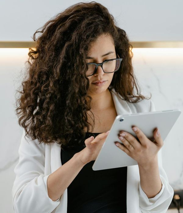 Professional woman with glasses reviewing business analytics on tablet device